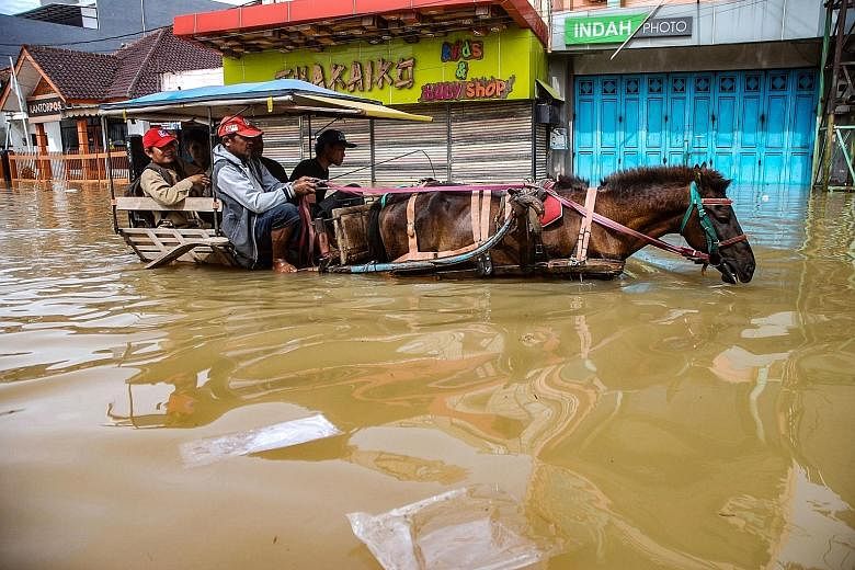 Residents making their way via horse cart along a flooded road in a Bandung village on Thursday as rain hammered West Java.