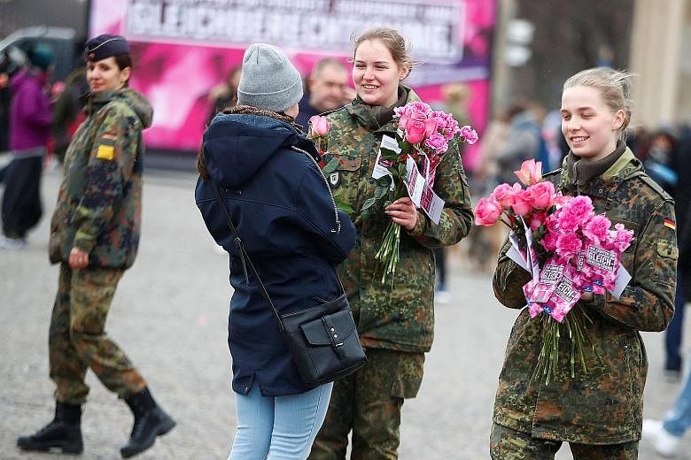 IN SOUTH KOREA: South Korean women dressed as witches with placards supporting feminism during a protest yesterday in Seoul. IN GERMANY: Female soldiers of the Bundeswehr, or German armed forces, giving out flowers to women near the Brandenburg Gate 