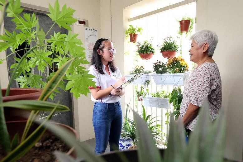 Neighbour Cares volunteer Marilyn Lim, a 16-year-old Nan Hua High School student, speaking to a fellow Yuhua resident during one of her weekly visits to check in on elderly residents in the neighbourhood.