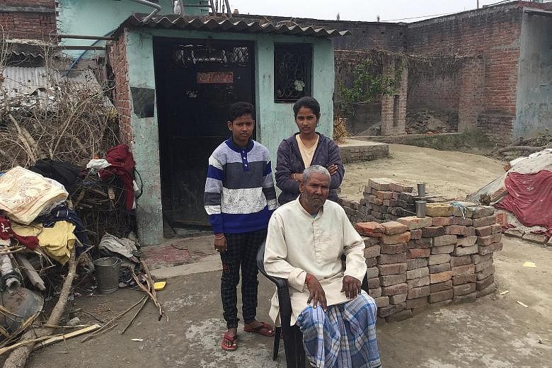 Mr Dhruvnarayan Sharma with his daughters Neha (left) and Jyoti (right) outside their house in Banwari Tola. A neurological disorder reduced mobility on 60-year-old Mr Sharma's right side, making him incapable of working at the modest barbershop he o