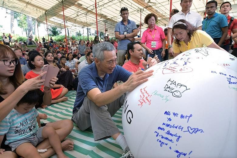 Prime Minister Lee Hsien Loong and Minister of State for National Development and Manpower Zaqy Mohamad penning their best wishes at the annual Marsiling Community Day yesterday, when the Marsiling Cares initiative was launched.