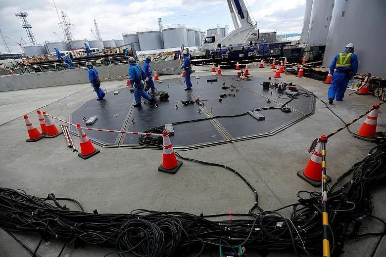 Workers building a storage tank (above) for radioactive water and doing decontamination work (left) at Tokyo Electric Power's tsunami-crippled nuclear power plant. Fukushima wants to be the domestic leader in robotics and drones, as well as in sustai