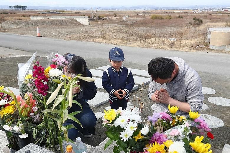 A family paying their respects to the victims of the 2011 earthquake, tsunami and Fukushima nuclear disaster in Japan.