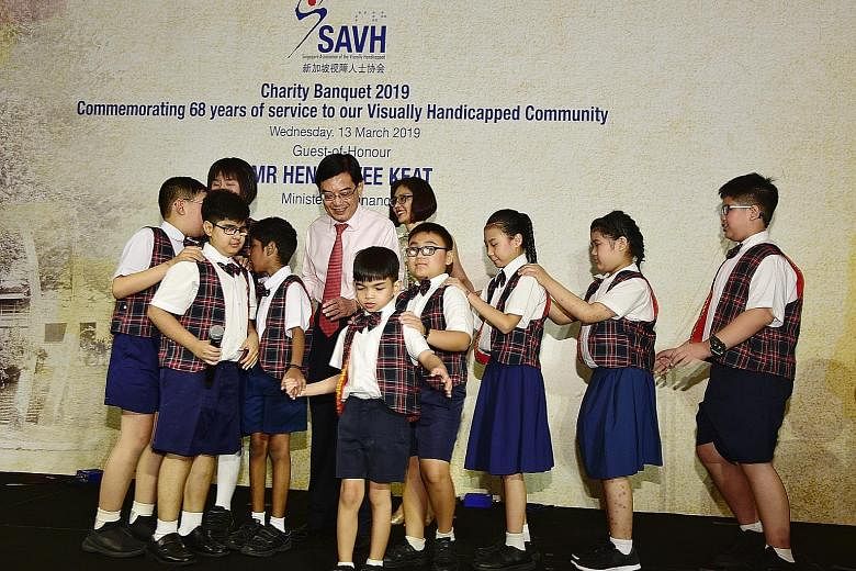 Finance Minister Heng Swee Keat and his wife Chang Hwee Nee with pupils from Lighthouse School, which provides special education to children with visual impairment and hearing loss. The pupils sang at a fund-raising dinner for the Singapore Associati