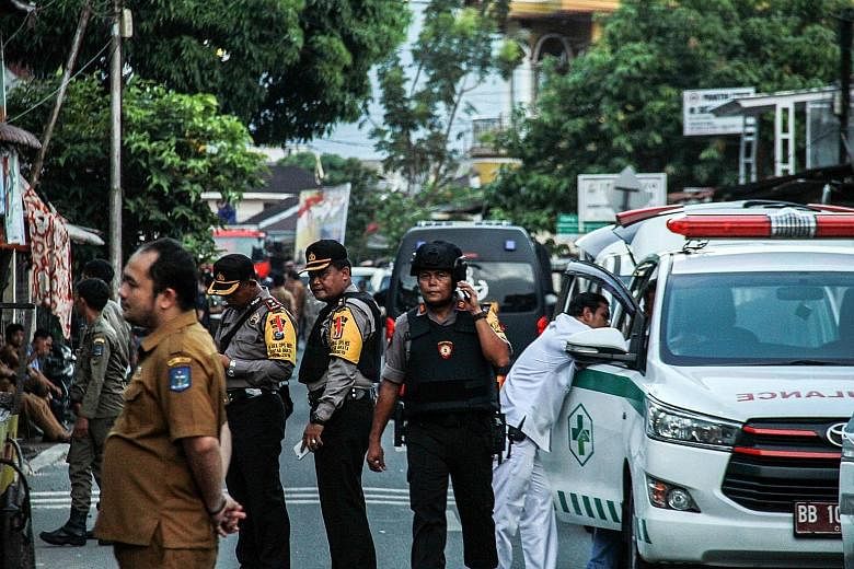 Indonesian policemen outside a house in Sibolga, North Sumatra, where a woman detonated a bomb, killing herself and her young child, yesterday. She was the wife of a militant who had been arrested the day before.