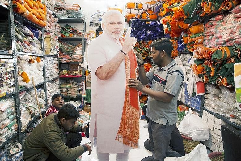 Workers with a cut-out of India's Prime Minister Narendra Modi at a store in New Delhi. The country's 900 million voters will be casting their ballots between April 11 and May 19.