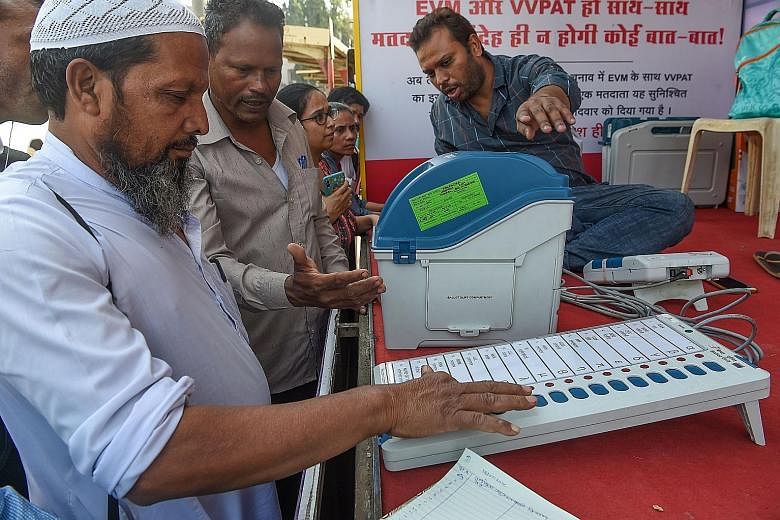 India will implement a paper audit trail for votes cast using the electronic voting machine (left). Election staff at a district collector's office in Ahmedabad last Thursday monitoring TV programmes to ensure the election code of conduct is being fo