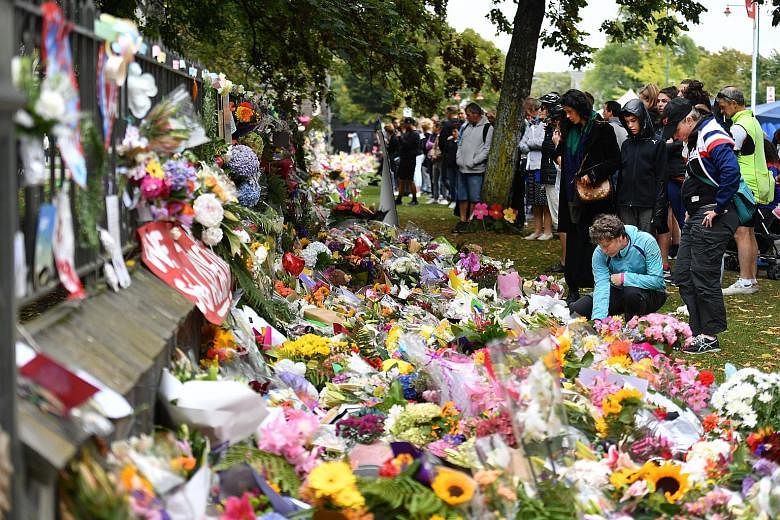 People placing flowers at a makeshift memorial for the massacre victims at the Christchurch Botanic Gardens yesterday.