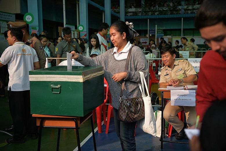 Thai voters queueing to cast their ballots during early voting at a polling station in Bangkok yesterday. In all, 80 parties are contesting 500 seats in the legislature, of which 350 are constituency seats and 150 are party-list seats. A woman castin