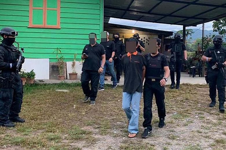Malaysian security officers taking away a suspected militant in Semporna, Sabah, during the latest anti-terror raids.