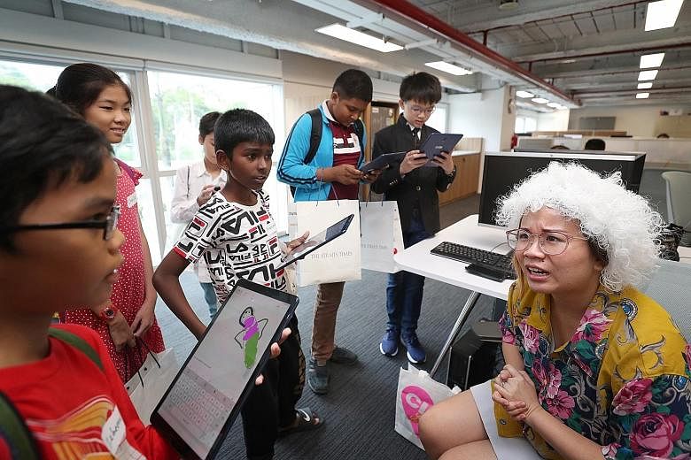 Zaheerul Hissham (far left) and Hahvenaas Poveneshwaran (third from left) with team members questioning Straits Times correspondent Rachel Au-Yong, who was playing the role of an old woman, during their visit to the newsroom yesterday. The beneficiar