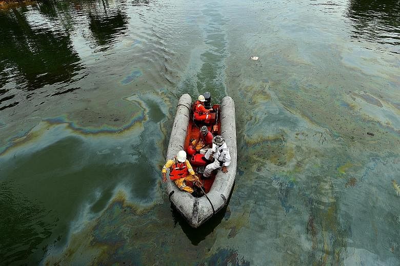 A boat carrying personnel from the Singapore oil spill response centre travelling in water stained with oil near the Changi jetty on Jan 5, 2017. The oil spill occurred in Johor near the Pasir Gudang Port on Jan 3, 2017, following a collision between
