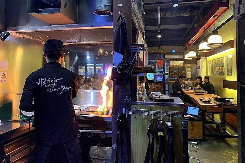 An employee of a Korean barbecue restaurant in Seoul roasting pork. The sale of pork rises when air pollution worsens in South Korea. The correlation stems from an old belief attributed to coal miners that the slippery pork oil helps cleanse dirt fro