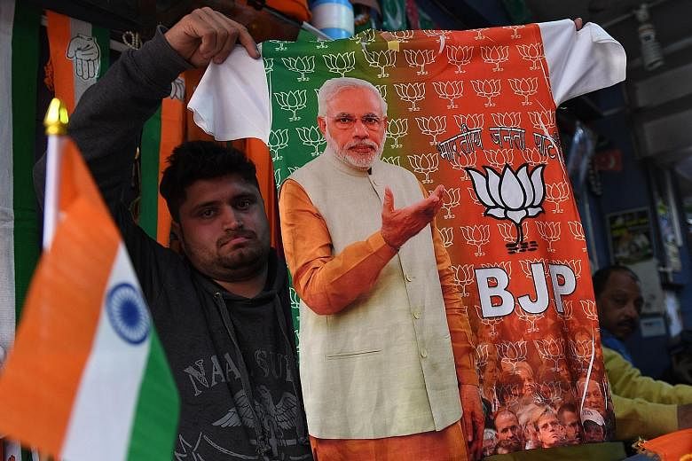 As election fever builds up, a shopkeeper in New Delhi shows a T-shirt with a picture of Prime Minister Narendra Modi printed on it.