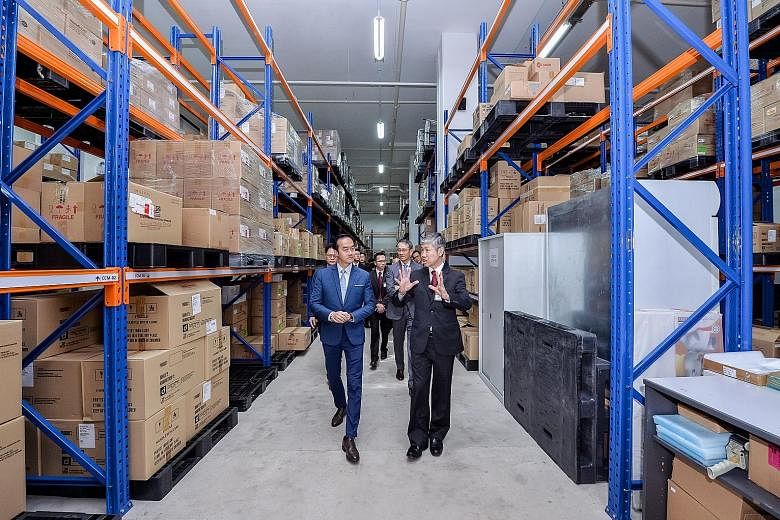 Senior Minister of State for Trade and Industry Koh Poh Koon (in blue), being briefed by Hyphens Pharma International chairman and CEO Lim See Wah yesterday, during a tour of the firm's new facility, which houses an automated packaging line with equi