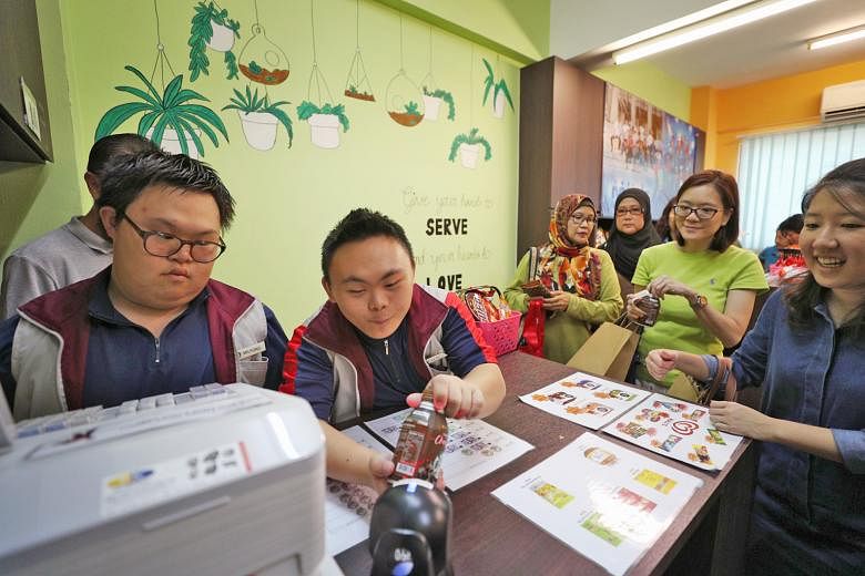 Minds adult beneficiaries wearing colourful socks to mark World Down Syndrome Day yesterday. Milford Loh (far left), 17, and Tan Jun Jie, 16, serving as cashiers at the minimart in Minds Lee Kong Chian Gardens School during its World Down Syndrome Da