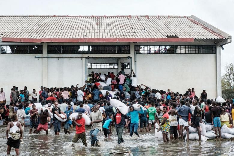 Looters grabbing sacks of rice in the Mozambique port city of Beira on Wednesday, after Cyclone Idai hit a week ago, causing devastating floods. The death toll in Mozambique has risen to 217, but President Filipe Nyusi has said it could exceed 1,000. Arou
