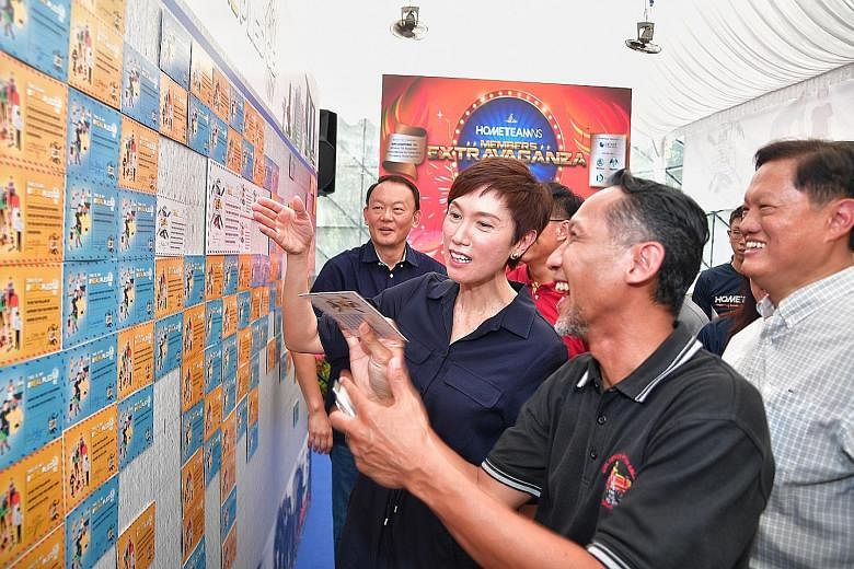 HomeTeamNS president Josephine Teo with two men who served in the Home Team previously, Mr Edwan Nizar Ahadan (foreground), 46, and Mr William Tan (in white), 62, looking at the pledges made by NSmen to reaffirm their commitment to serve and protect 