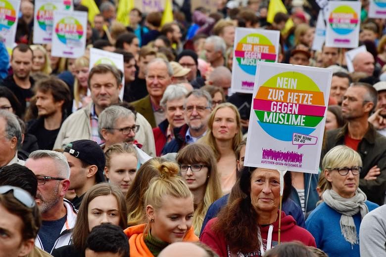 Placards at a rally in Germany last year said "No to hatred against Muslims". A study shows the number of attacks against Muslims has fallen there but there is "Islamophobia without Muslims" in Eastern Europe.