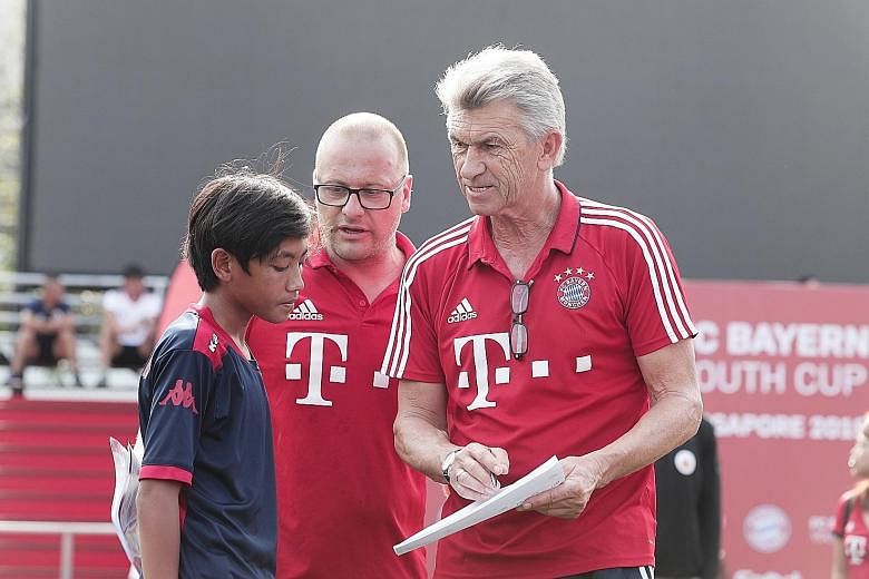 Bayern Munich great and World Cup winner Klaus Augenthaler (right), together with Sebastian Dremmler, head coach of Bayern's international programme, giving Nur Muhammad Asis Ijilrali some feedback at the FC Bayern Youth Cup Singapore finals yesterda