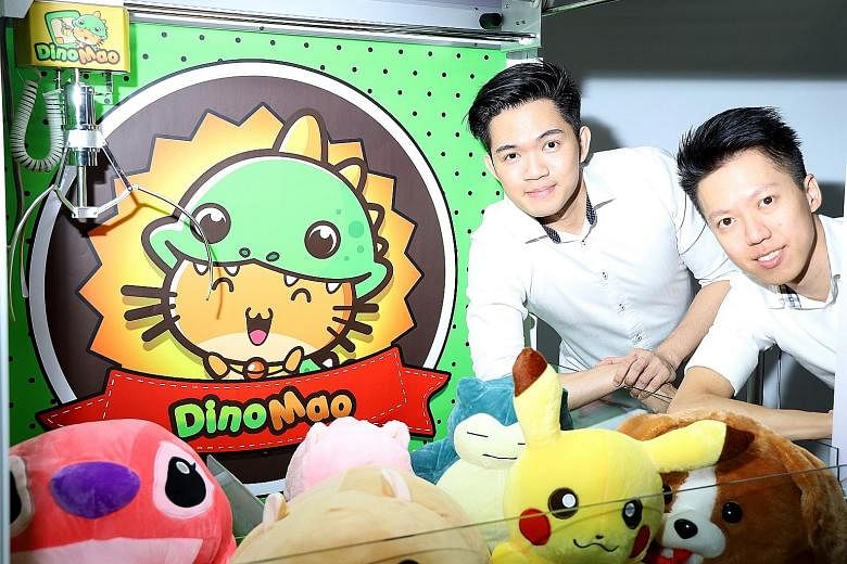 DinoMao founders Jeremy Foo (left) and Jacky Goh with one of their claw machines.