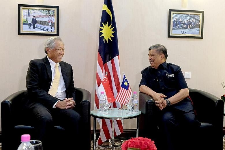 Singapore's Defence Minister Ng Eng Hen exchanging views with Malaysia's Minister of Defence Mohamad Sabu on the sidelines of the Langkawi International Maritime and Aerospace Exhibition yesterday.