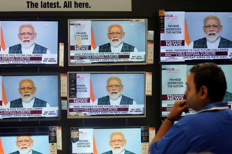 Indian Prime Minister Narendra Modi - shown here on TV screens inside a Mumbai showroom - addressing the nation yesterday to announce the successful anti-satellite missile test. He said that a missile travelled nearly 300km from earth and hit the sat