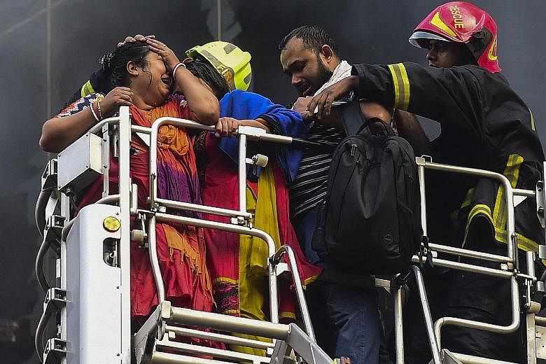 A Bangladeshi survivor reacting after being rescued by firefighters from a burning office building in Dhaka yesterday.