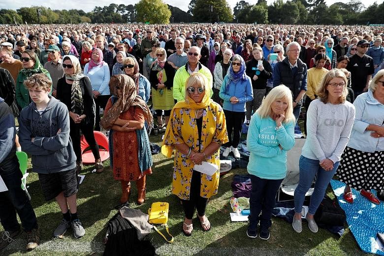 People, including some women wearing headscarves, attending the memorial service at Hagley Park in Christchurch.