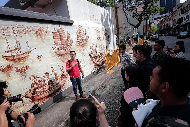 Mr Yip Yew Chong, who painted a 44m-long mural behind the Thian Hock Keng Temple depicting the life of early Hokkien immigrants when they first arrived in Amoy Street, introducing the artwork to participants of the preview of the Singapore Maritime Trail 