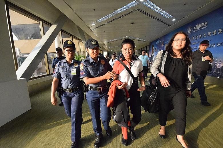 Philippine journalist Maria Ressa (centre) being escorted from Manila's international airport yesterday after being served with an arrest warrant.