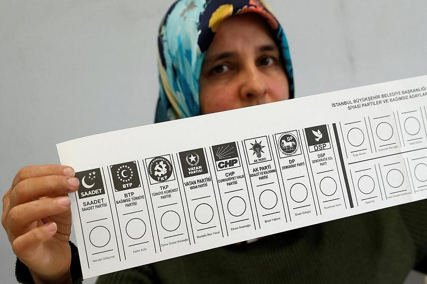 An election official holding up a ballot card at a polling station in Istanbul. Yesterday's elections were the first since Turkish President Recep Tayyip Erdogan assumed sweeping presidential powers last year.