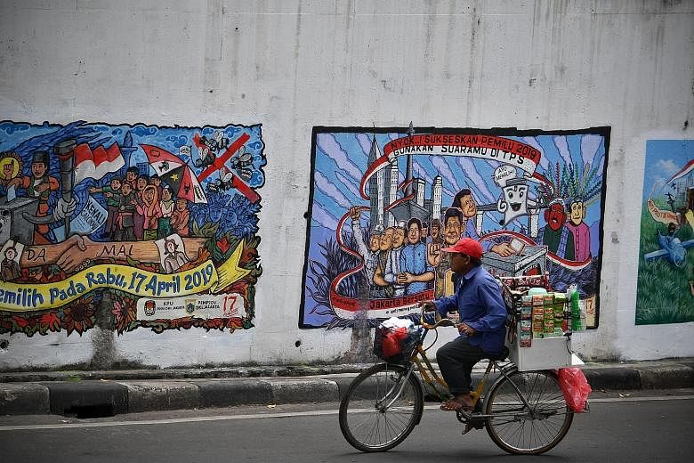 A vendor cycling past political murals on a wall in Central Jakarta yesterday. The Prabowo-Sandiaga team claims there are irregularities in the final voter list which could lead to electoral fraud if not resolved.