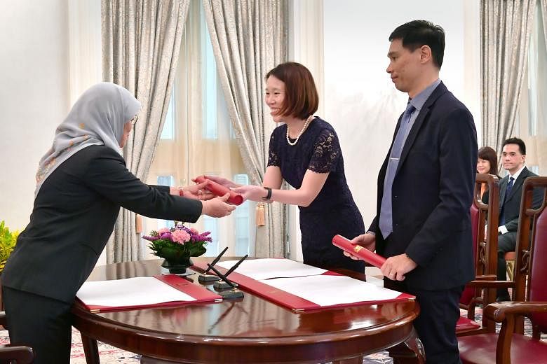 President Halimah Yacob handing letters of appointment to Ms Lai Wei Lin and Mr Joseph Leong Weng Keong at the Istana as they were sworn into their new roles in the Government yesterday. Mr Leong was appointed Permanent Secretary (Defence Development