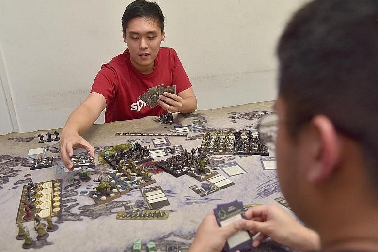 Illustrator Russell Ng (far left), 29, a Game Of Thrones fan, playing the A Song Of Ice And Fire tabletop miniatures game at Gamersaurus Rex. The game, which launched six months ago after a successful Kickstarter bid, has tiny figures (above) that th