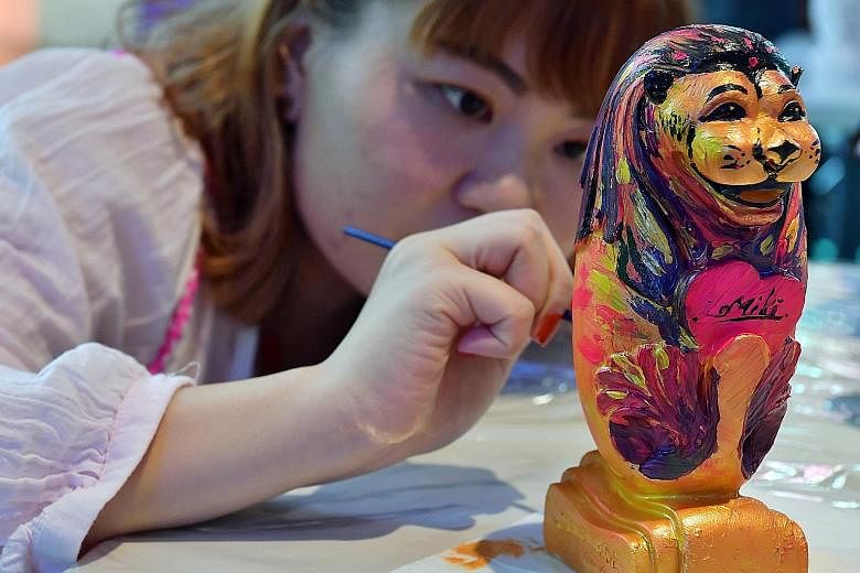 Graphic designer Lim Mei Kee, 27, painting a 20cm-tall miniature Merlion at a workshop organised under the first Lion's Pride event at Orchard Gateway. Each mini Merlion costs $38 for members of the public. There is also a 1.6m-tall Merlion in the ma