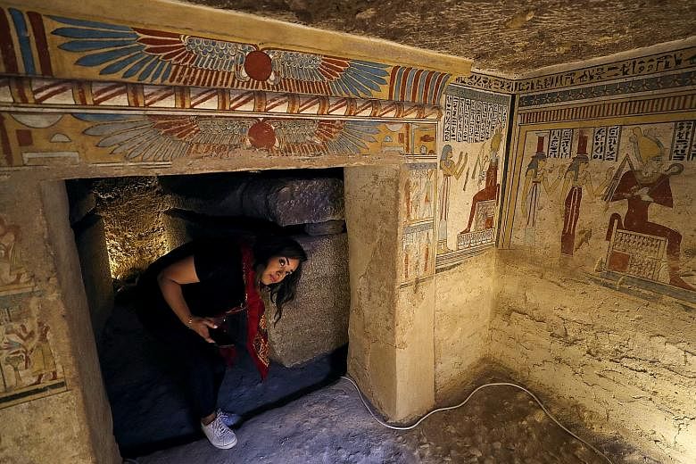 An archaeologist holding an ancient mummified bird (above), found inside the tomb, which dates back more than 2,000 years. Also discovered were mummified mice and falcons (left). A tourist surrounded by paintings inside the newly discovered burial si