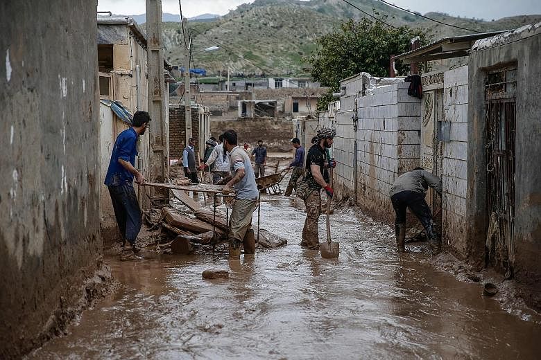 Men clearing away mud yesterday, following floods in the city of Mamulan in Iran's Lorestan province. Thousands have been displaced by flooding in the province.