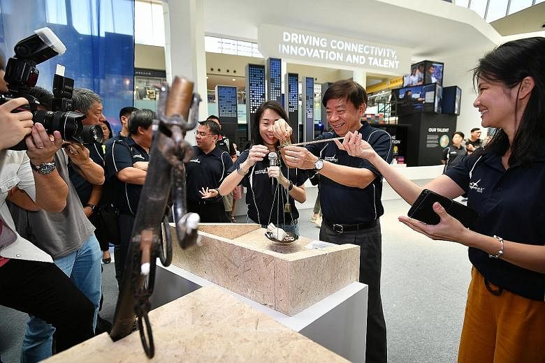 Transport Minister Khaw Boon Wan trying out a daching, or weighing scale, at an exhibition yesterday at Marina Square's central atrium, where visitors can trace Singapore's maritime history. ST PHOTO: LIM YAOHUI