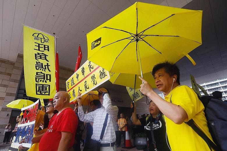 Supporters of the "Umbrella Nine" raising yellow umbrellas in protest outside a Hong Kong district court ahead of the verdict yesterday.