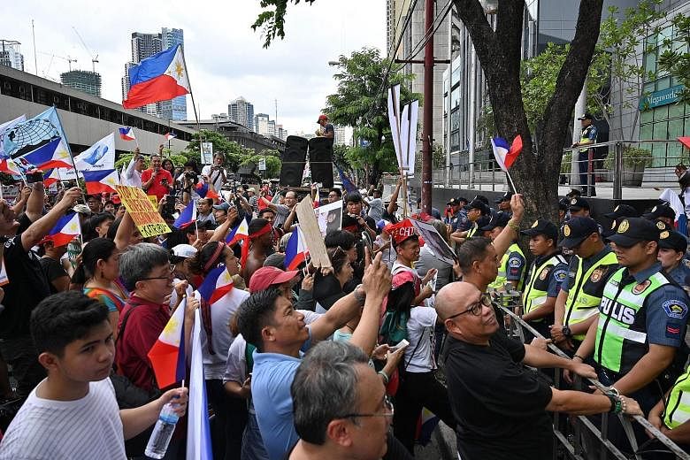 Anti-China protesters raising clenched fists and national flags while shouting slogans during a protest in front of the Chinese embassy in the financial district of Manila yesterday, as policemen stand guard. The marchers, numbering about 1,000, disp