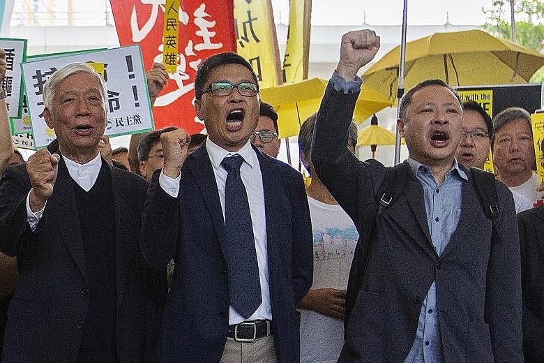 The three prominent leaders behind the Umbrella Movement rallies - (from far left) Baptist minister Chu Yiu Ming, sociology professor Chan Kin Man and law professor Benny Tai - outside the court on Tuesday. PHOTO: EPA-EFE