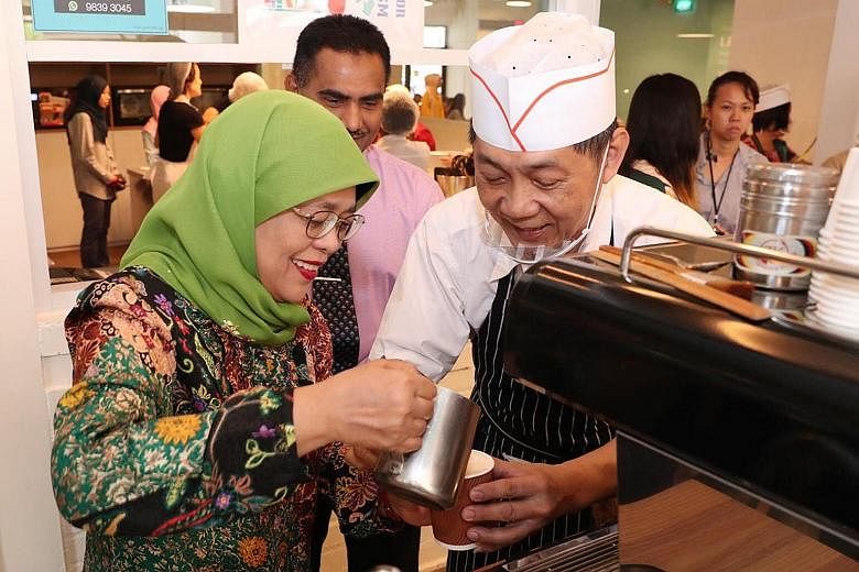 President Halimah Yacob joining senior volunteers who run the SASCO@Khatib Activity Centre's in-house cafe to brew gourmet coffee during her visit yesterday. The centre in Yishun is a community facility that promotes senior learning and volunteerism.