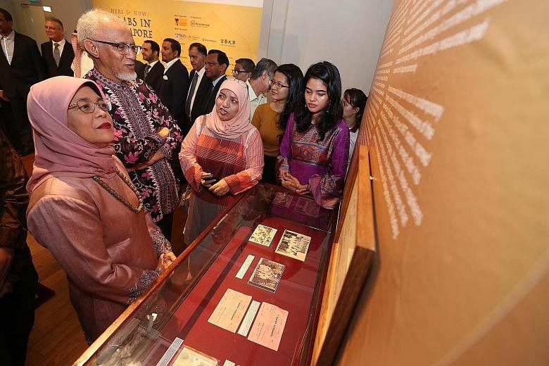 President Halimah Yacob and her husband, Mr Mohamed Abdullah Alhabshee - who is of Arab descent - being briefed on the exhibits at the Here And Now: Arabs In Singapore exhibition at The Arts House yesterday.