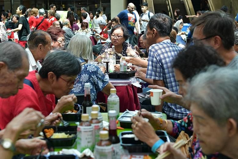 People tucking into a meal at Food Bank Singapore's inaugural community engagement event yesterday at City Square Mall in Kitchener Road. The day's activities included cooking demonstrations and talks on food insecurity and food waste. There were als