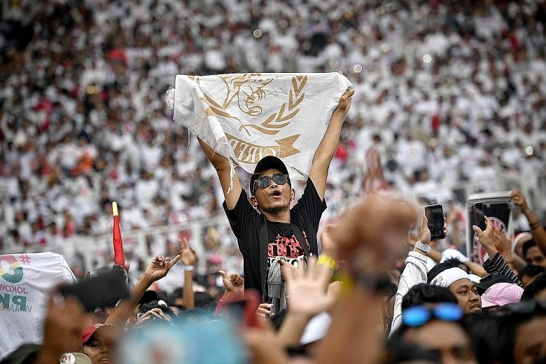 A supporter raising a flag during a concert at President Joko Widodo's final campaign rally yesterday in Jakarta. ST PHOTO: ARIFFIN JAMAR