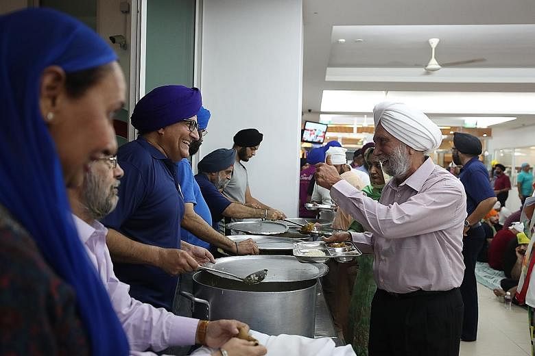 Minister for Communications and Information S. Iswaran (third from left), Sikh Advisory Board chairman Surjit Singh (second from left) and former MP Inderjit Singh (fifth from left) serving dinner to members of the Sikh community at the Central Sikh 