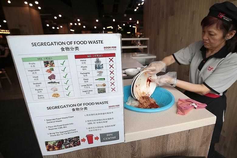 An employee segregating food waste from general waste at the Koufu foodcourt in Jem mall. Porous baskets at the collection points first help to separate liquids from solid food. The liquid waste is then double-bagged, before the bags are taken to the