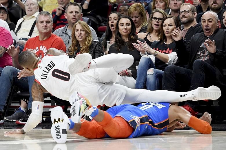 Portland's Damian Lillard is tripped by Oklahoma City's Russell Westbrook at Moda Centre in Oregon on Sunday. The Blazers won 104-99 - their first play-off victory since the 2015-16 season.