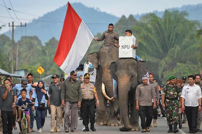 Elephants being used to transport election materials in Trumon, southern Aceh, yesterday. People turning up to cast their votes at a flooded polling station in Bandung, West Java. Officials counting ballot papers at a polling station in Bendungan Hil